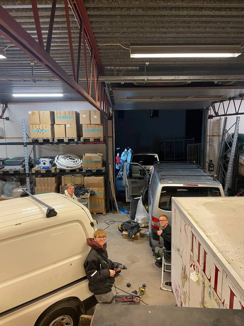 Flere personer jobber i et lager med biler
